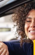 Cliente da Legalize ao volante do próprio carro, sorrindo